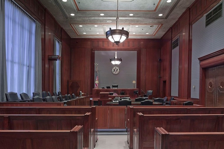 looking down the isle of a courtroom with wooden pews and furniture.